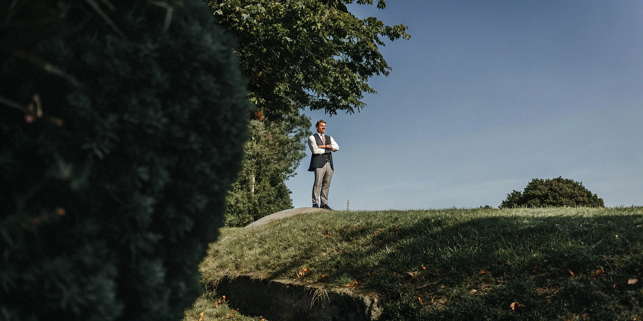 Ordained minister in formal attire stands confidently outdoors.