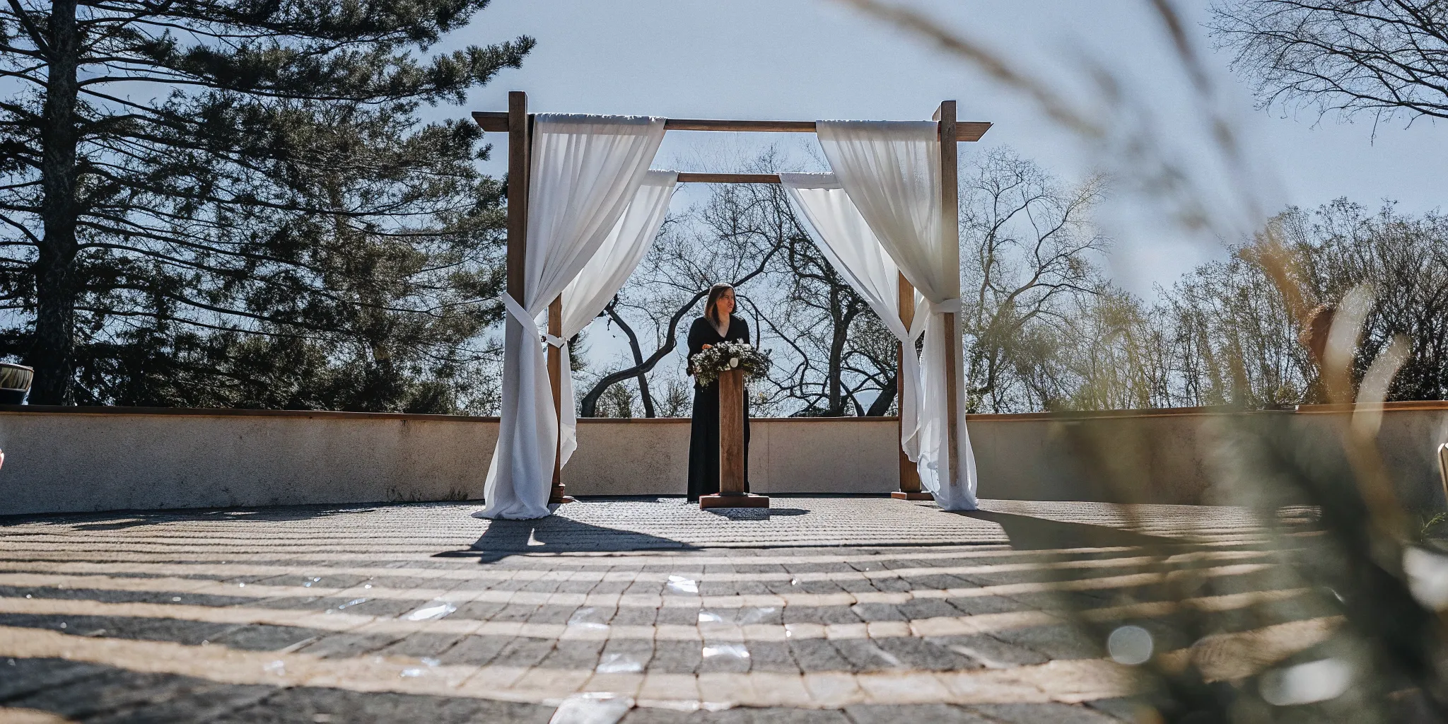Wedding officiant under a decorated arch at a California wedding ceremony.